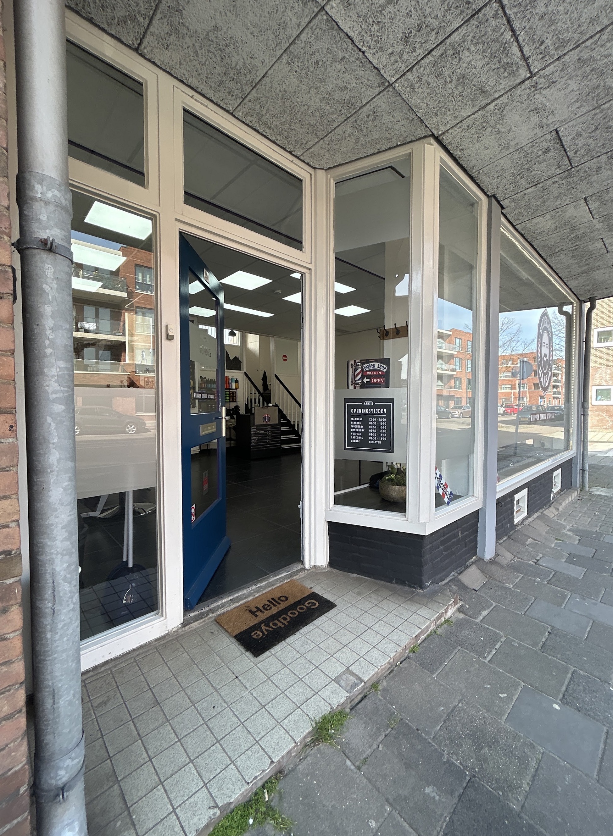 De ingang van Barbershop Hansie aan de P.C. Hooftlaan, met de glazen deur en de etalage