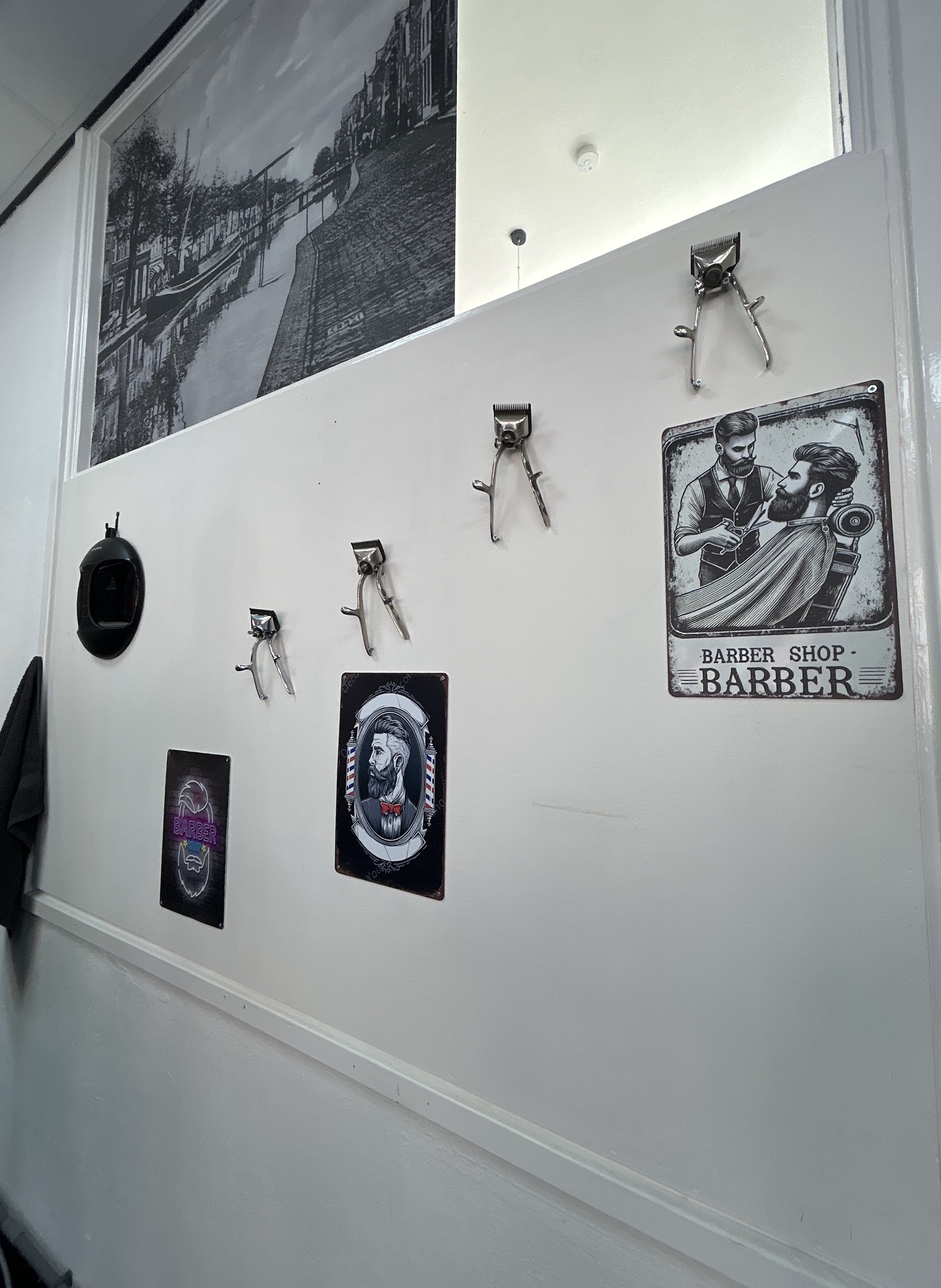 Een witte muur met oude tondeuses en barberposters